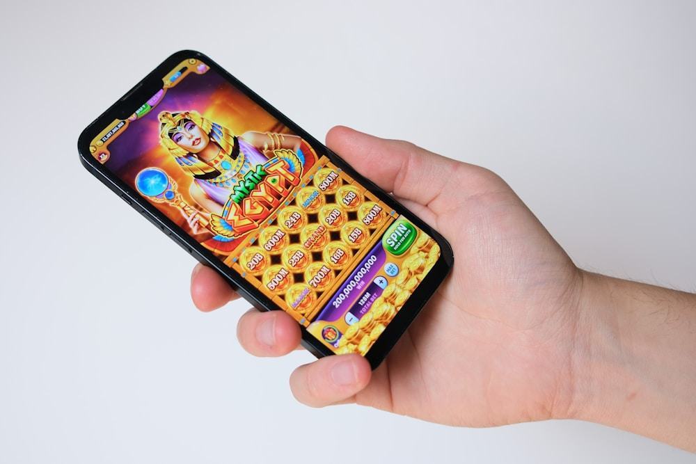 Tangan memegang ponsel dengan permainan slot bertema Mesir kuno